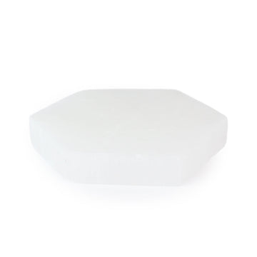 Angled view of a hexagonal selenite coaster displaying its luminous surface and edges, highlighting the crystal’s soft sheen.